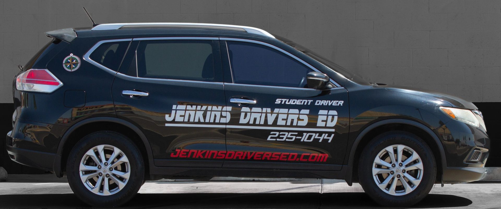 Dark blue Nissan Rogue training vehicle with Jenkins Drivers Ed branding